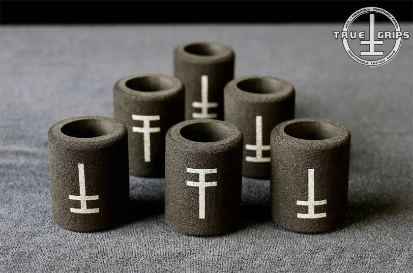 A collection of black disposable memory foam grip covers for tattooing, with the brand logo 'True Grips' visible in the top right corner.