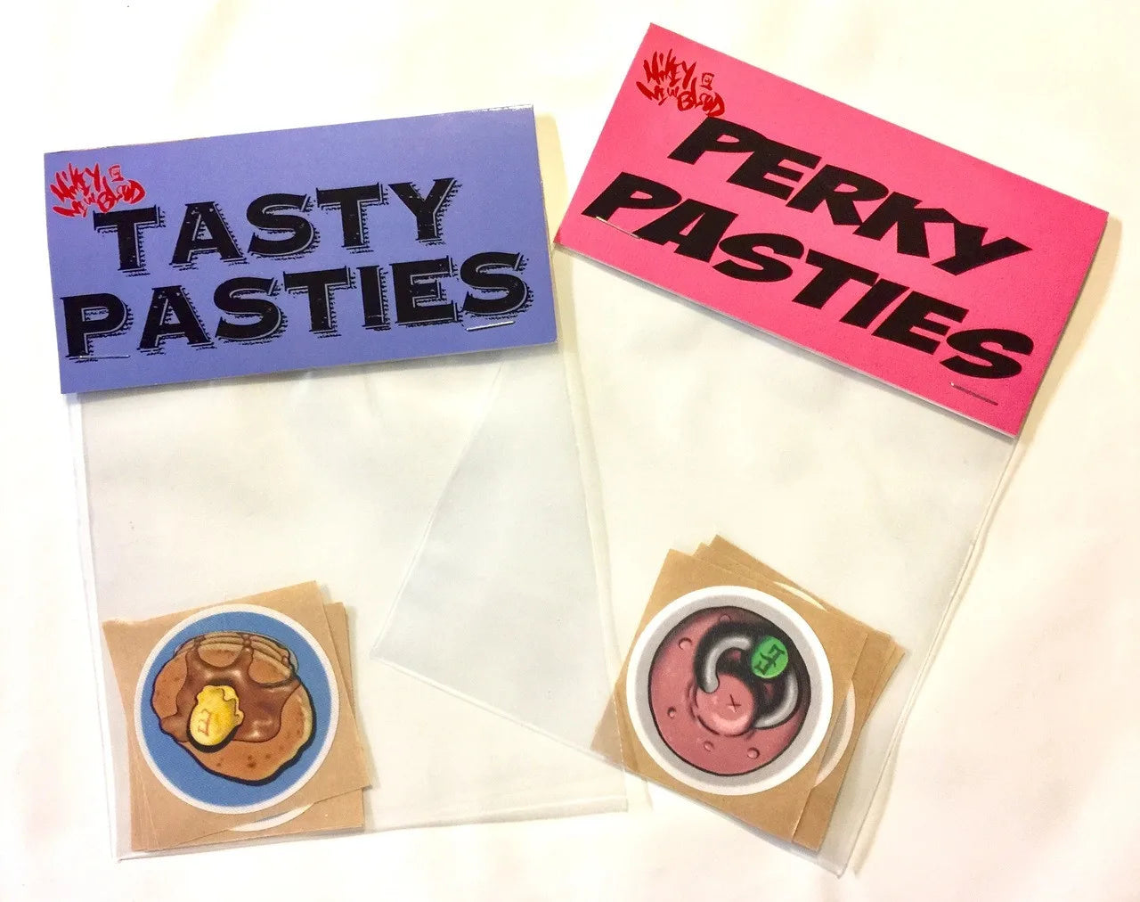 When censorship required - Two packs of disposable pasties, one labeled 'TASTY PASTIES' with an image of a bacon and egg design, and one labeled 'PERKY PASTIES' with a pancakes and waffles design.