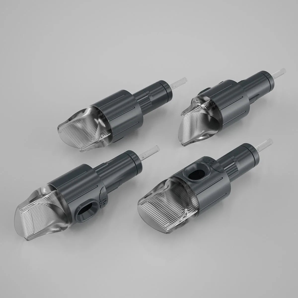 A set of four cartridge tattoo needles with transparent caps, predominantly gray in color.
