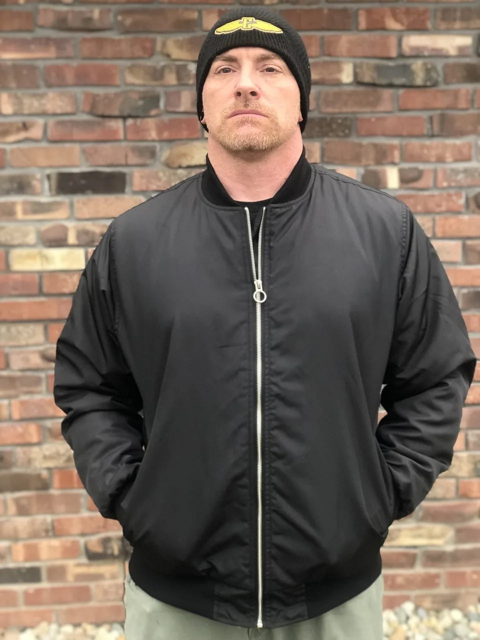 a man wearing a black electrum bomber jacket - zipped up 