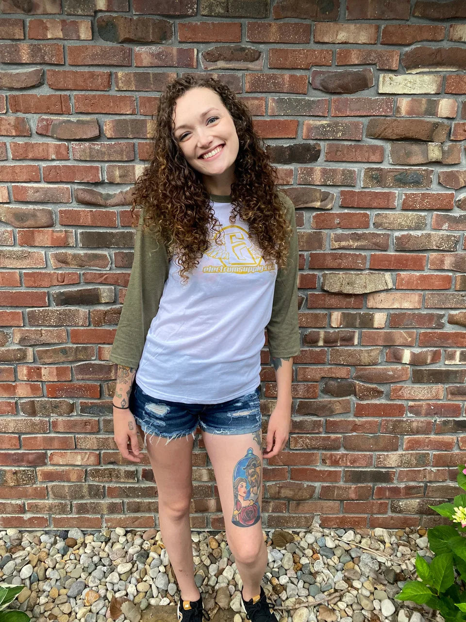 a woman wearing a 3/4 length shirt with a yellow electrum logo on the front