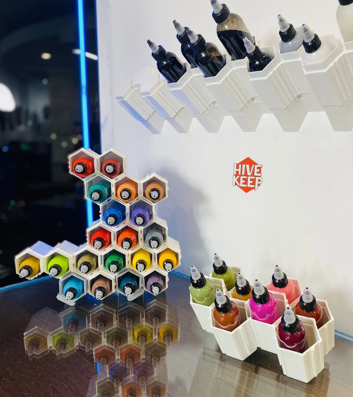 A creative art storage unit called HIVE KEEP, featuring multiple compartments with colorful tattoo ink bottles, displayed on a counter.