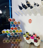 A creative art storage unit called HIVE KEEP, featuring multiple compartments with colorful tattoo ink bottles, displayed on a counter.