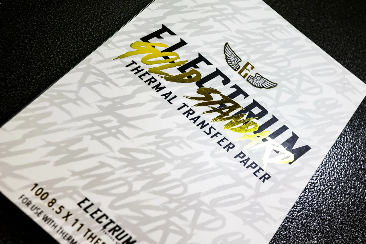 A close-up of a sheet of Electrum Gold Standard Thermal Transfer Paper with a tattoo design, indicating the paper's use for transferring patterns onto skin.