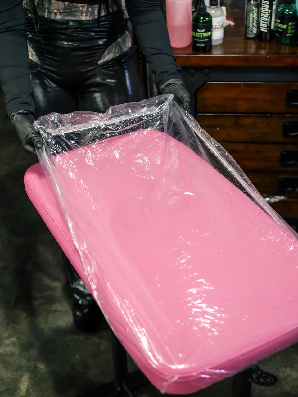 person applyiing the tattoo chair protective plastic cover