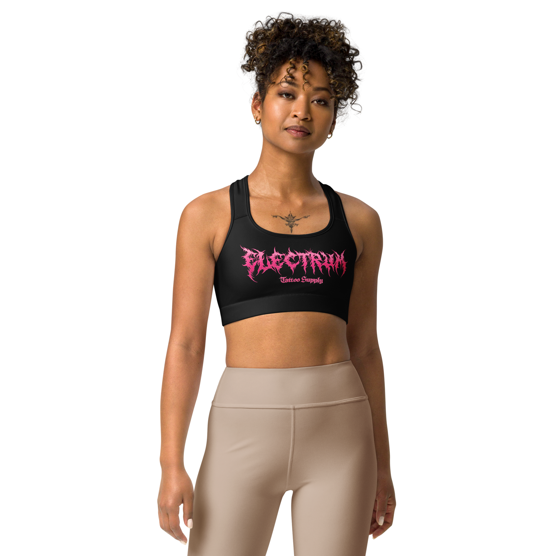 Woman wearing a black sports bra with pink metal lettering saying electrum tattoo supply