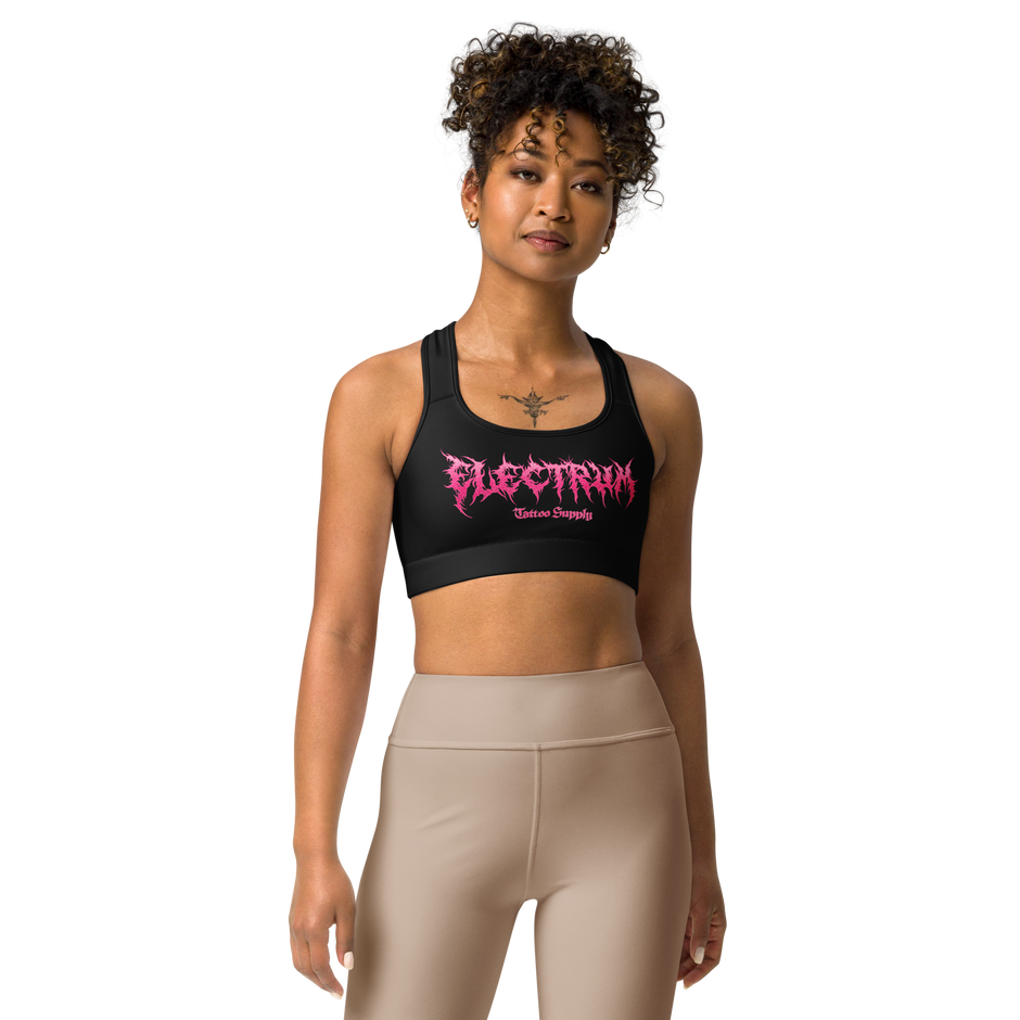 Woman wearing a black sports bra with pink metal lettering saying electrum tattoo supply